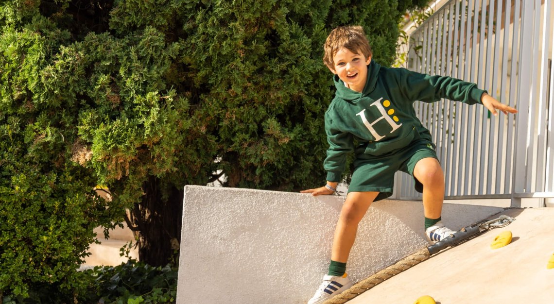 Male student at Hastings School is outside sat on a step, smiling.
